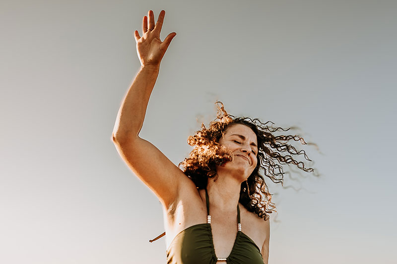Cécile, danse-art-thérapeute qui danse devant le ciel, le sourire aux lèvres.